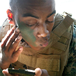 U.S. Marine Corps Cpl. Emery Williams looks at a mirror as he applies camouflage paint on his face at Marine Corps Base Hawaii, May 19, 2010.